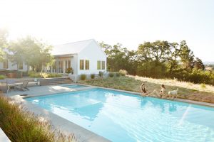 June2015-Trulia-5-Home-Upgrades-That-Wont-Add-Enough-Value-sisters-sitting-on-edge-of-backyard-pool